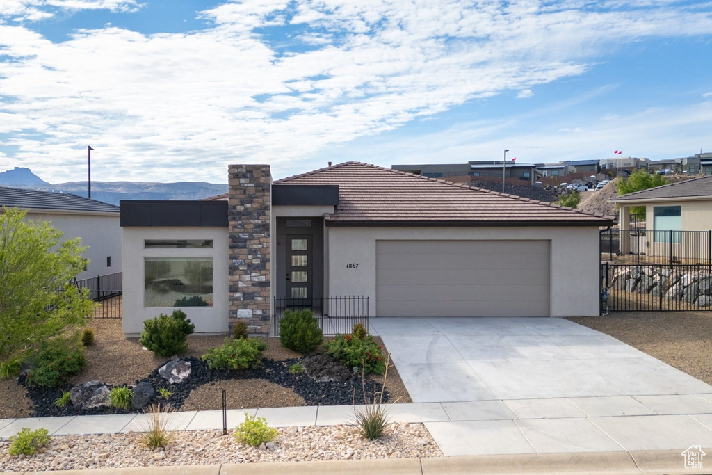 Contemporary house featuring fence, stucco siding, a garage, and concrete driveway