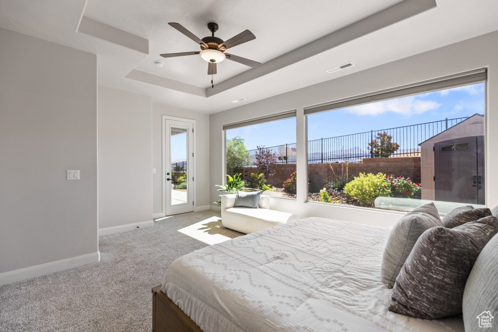 Bedroom featuring a tray ceiling, access to exterior, baseboards, carpet floors, and a ceiling fan