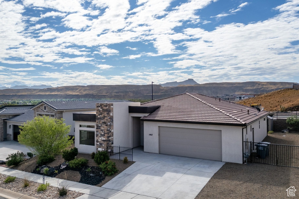 Modern home featuring a mountain view, stucco siding, an attached garage, concrete driveway, and fence