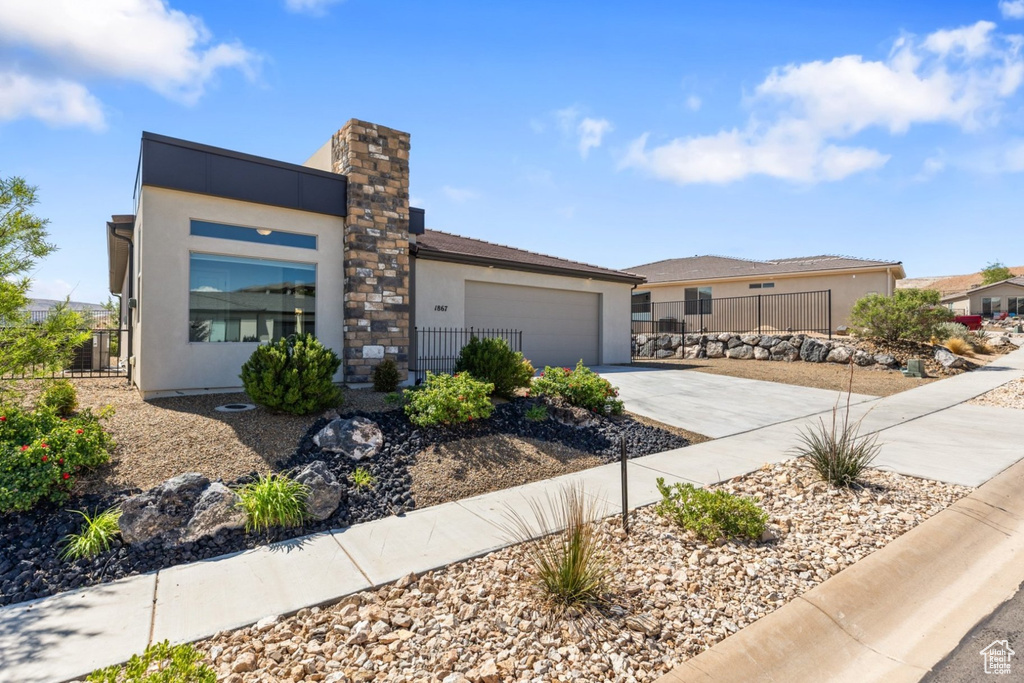 View of front of house featuring driveway, stucco siding, a garage, and fence