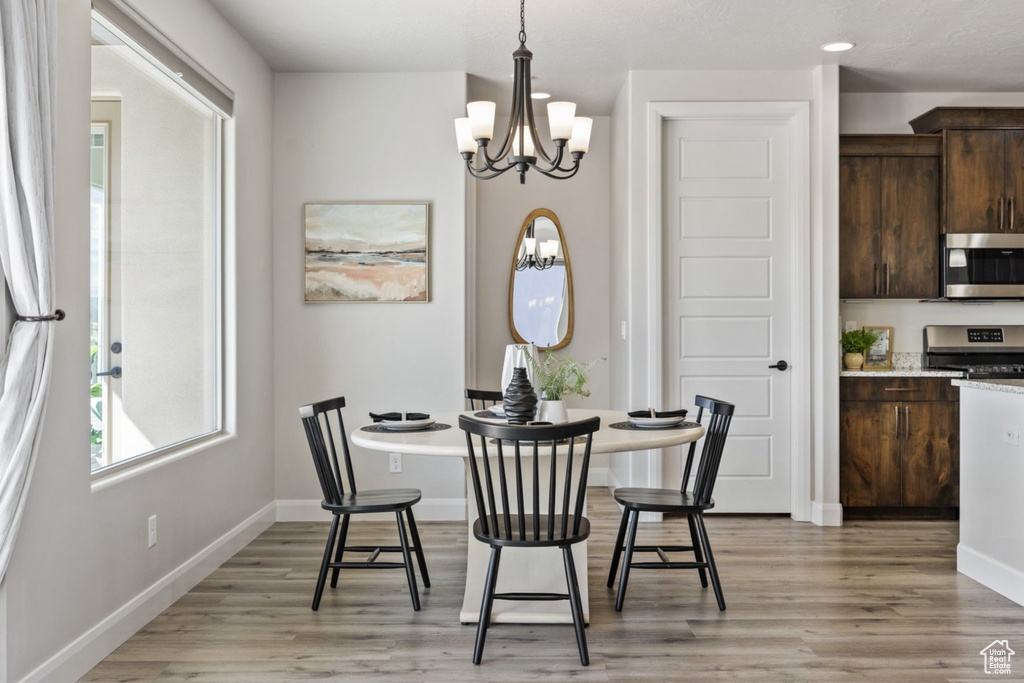 Dining room featuring a chandelier, light wood finished floors, baseboards, and recessed lighting
