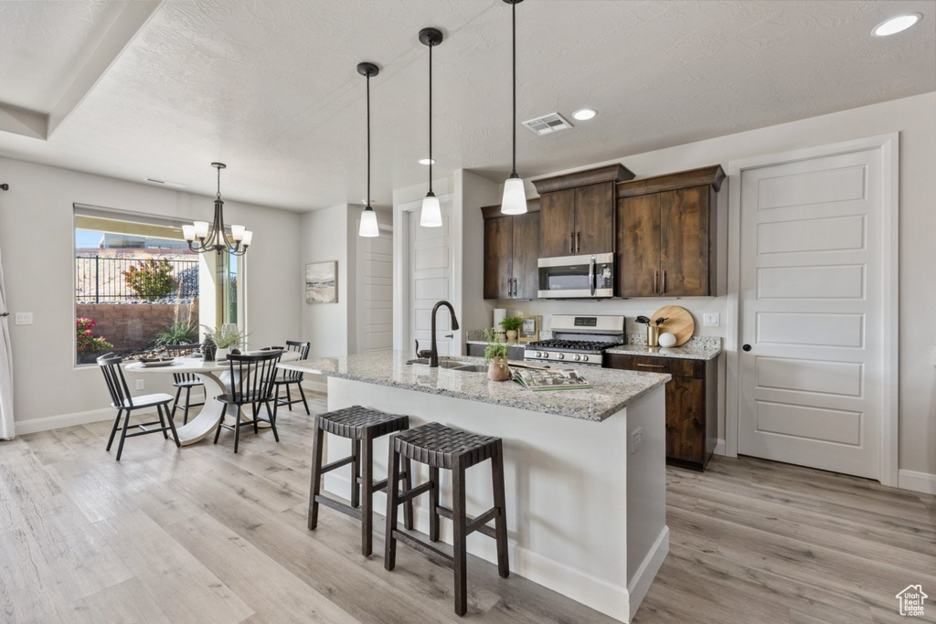 Kitchen featuring stainless steel appliances, light wood-style floors, dark brown cabinetry, recessed lighting, and baseboards
