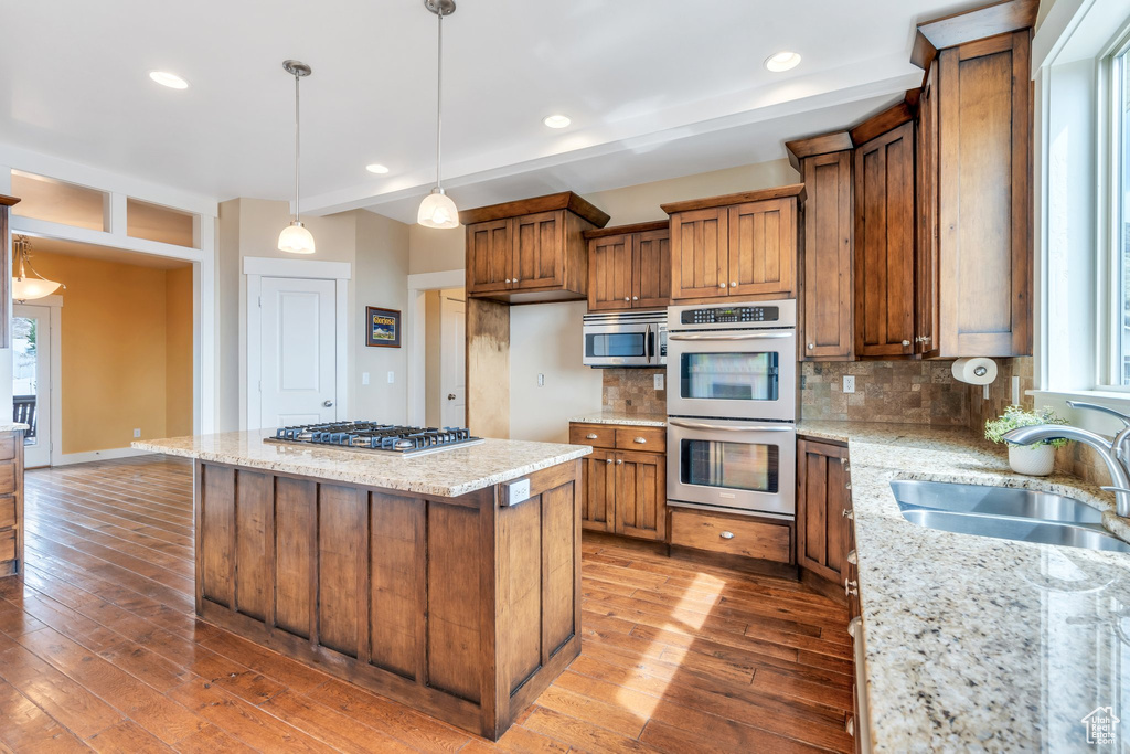 Kitchen with hardwood / wood-style flooring, a sink, brown cabinets, and appliances with stainless steel finishes