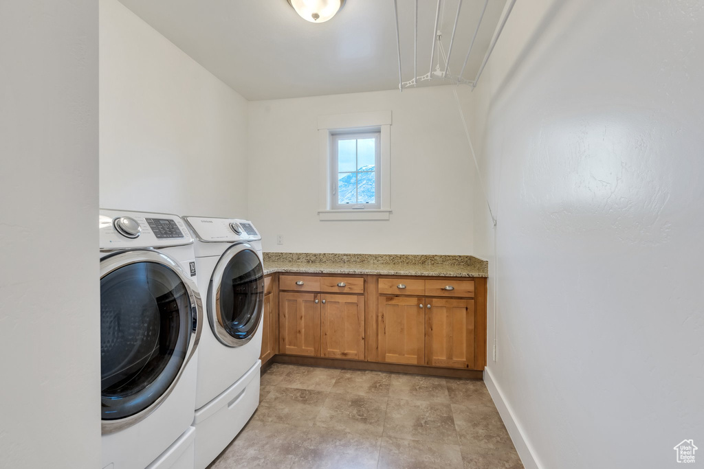 Laundry area with washing machine and clothes dryer, cabinet space, baseboards, and attic access