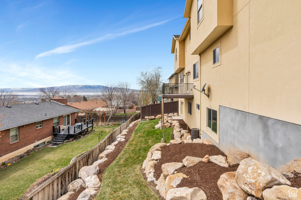 View of yard with a balcony, a deck with mountain view, a fenced backyard, a residential view, and cooling unit