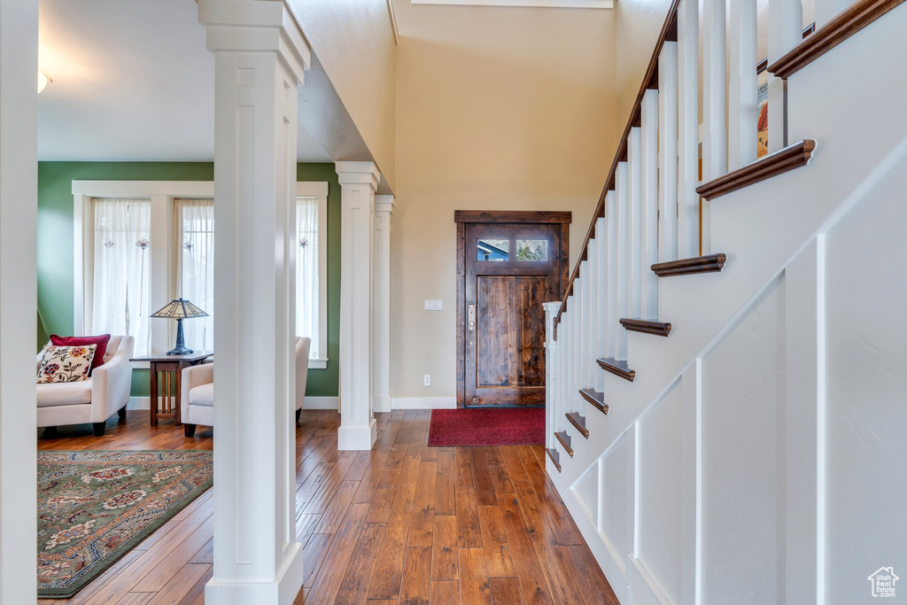 Entryway with wood-type flooring, baseboards, stairs, and ornate columns