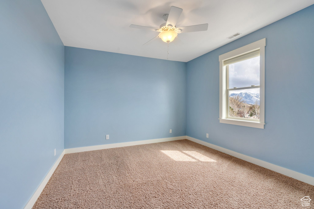 Carpeted spare room featuring a ceiling fan, baseboards, and visible vents