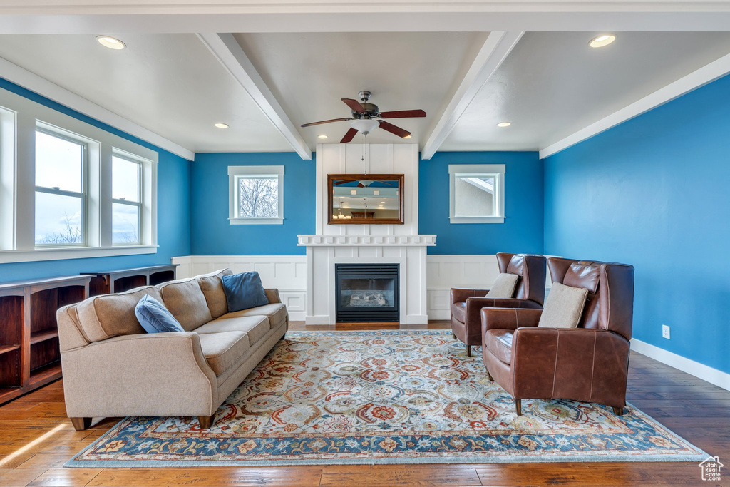 Living room with recessed lighting, a ceiling fan, beam ceiling, a glass covered fireplace, and wood-type flooring