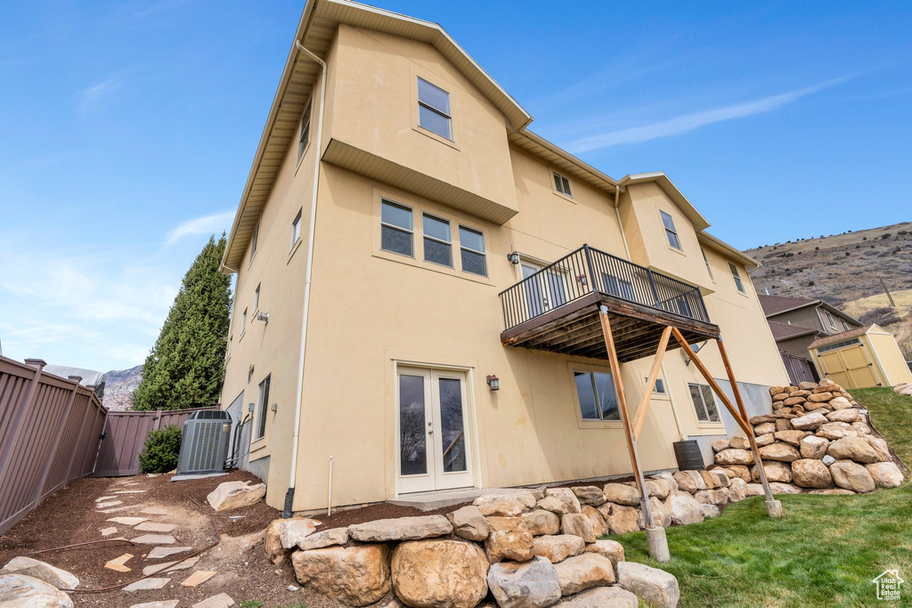 Rear view of house featuring stucco siding, a gate, a fenced backyard, and french doors