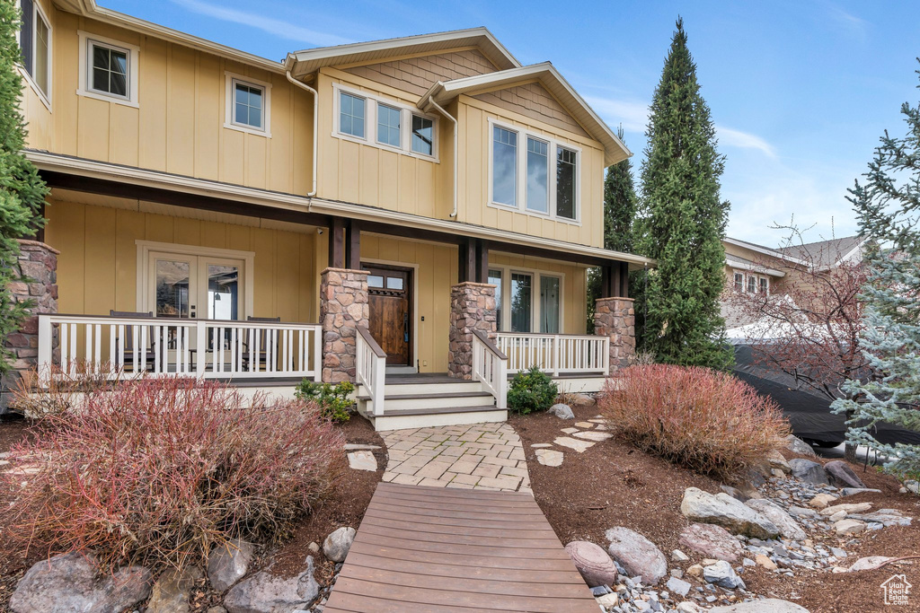 View of front of home featuring covered porch, stone siding, and board and batten siding