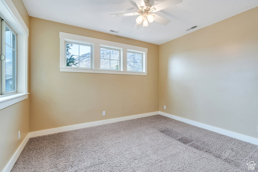 Empty room featuring baseboards, carpet floors, ceiling fan, and visible vents