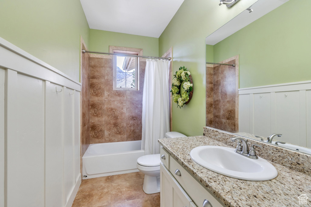 Bathroom featuring toilet, vanity, a wainscoted wall, and shower / tub combo