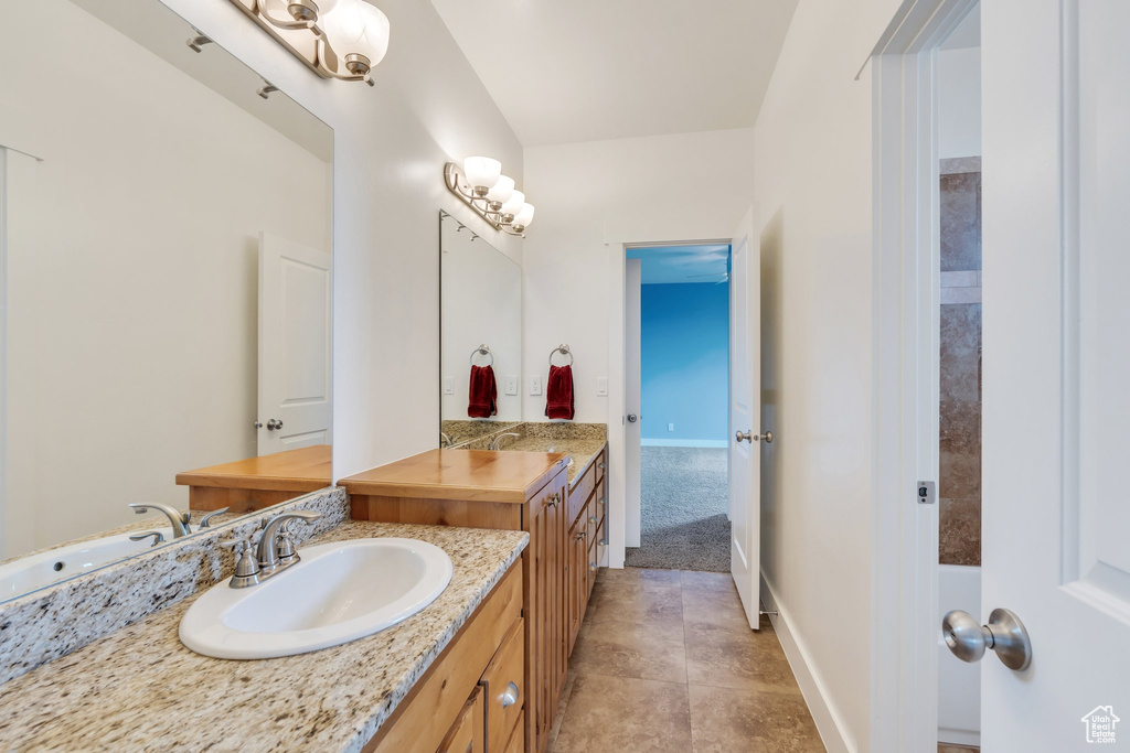 Bathroom featuring a sink, two vanities, and baseboards