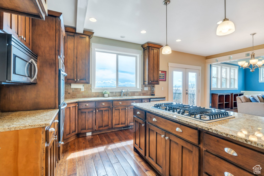 Kitchen with light stone countertops, stainless steel appliances, dark wood-style floors, and decorative backsplash