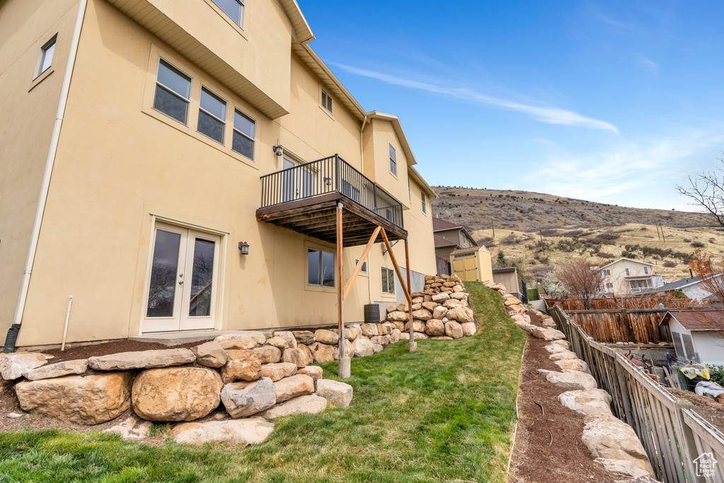 View of yard featuring a balcony, central air condition unit, fence, a mountain view, and french doors