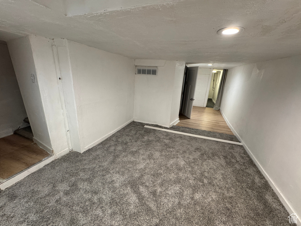 Finished below grade area with carpet flooring, a textured ceiling, and baseboards