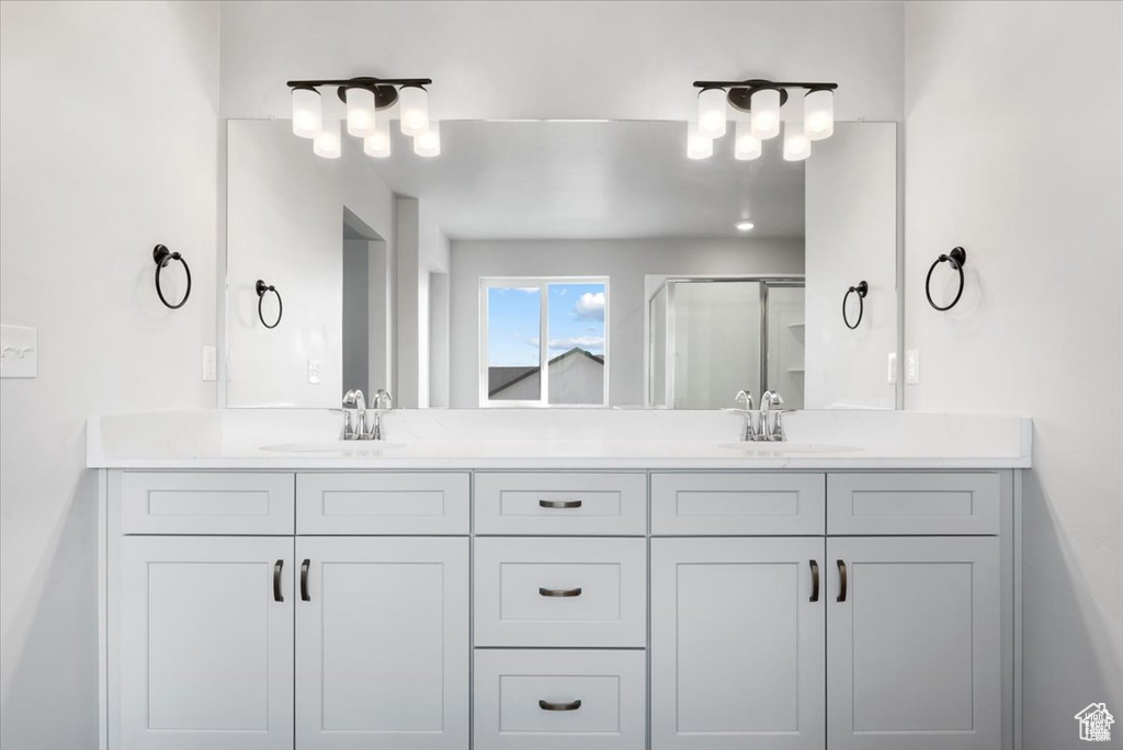 Full bath with double vanity, a sink, and a shower stall