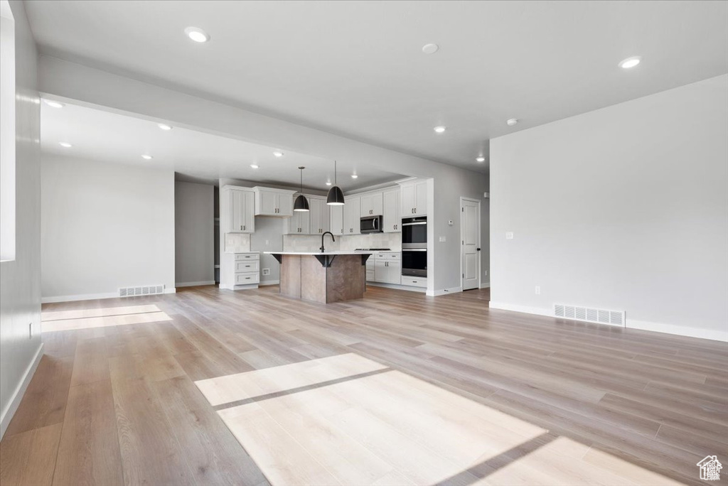 Unfurnished living room with light wood-style flooring, visible vents, and recessed lighting