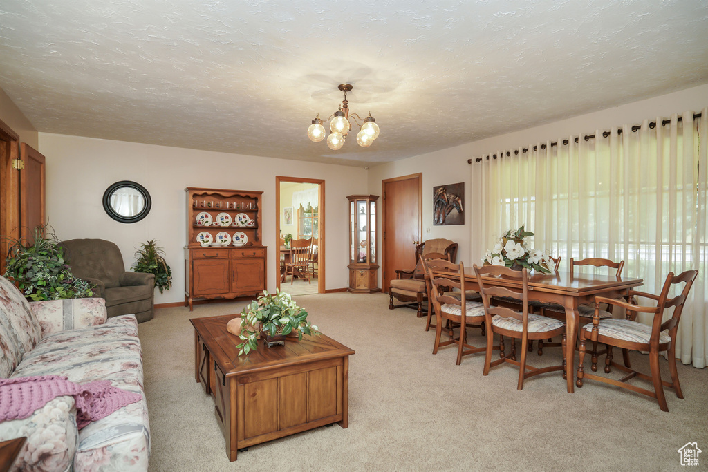 Living room with light colored carpet, a textured ceiling, baseboards, and a chandelier