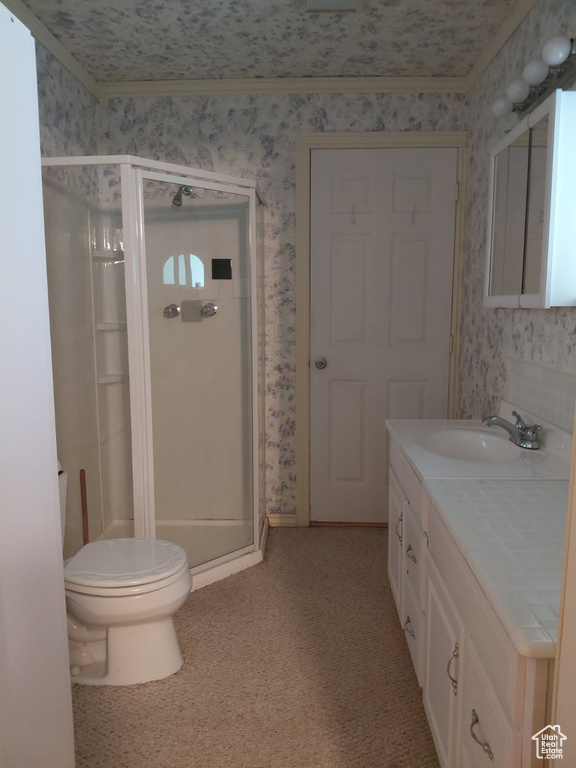 Full bathroom featuring vanity, a stall shower, toilet, and wallpapered walls