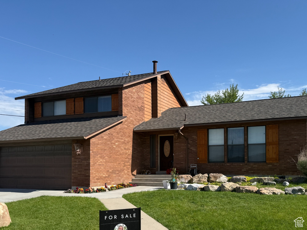 View of front facade featuring brick siding, driveway, an attached garage, and roof with shingles