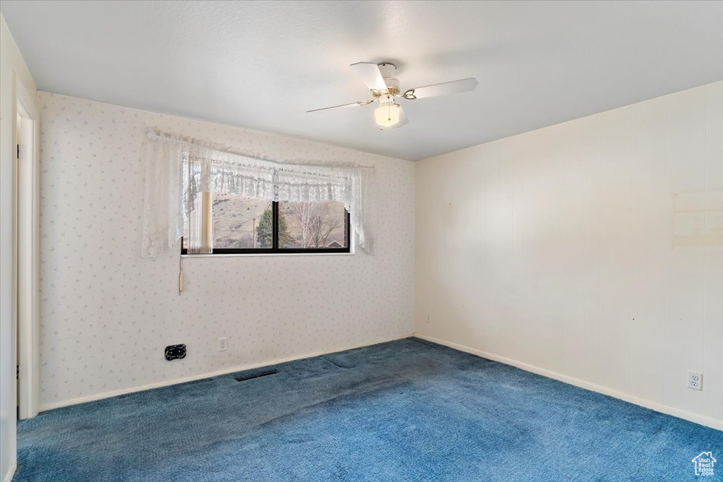 Carpeted spare room featuring baseboards, visible vents, ceiling fan, and wallpapered walls