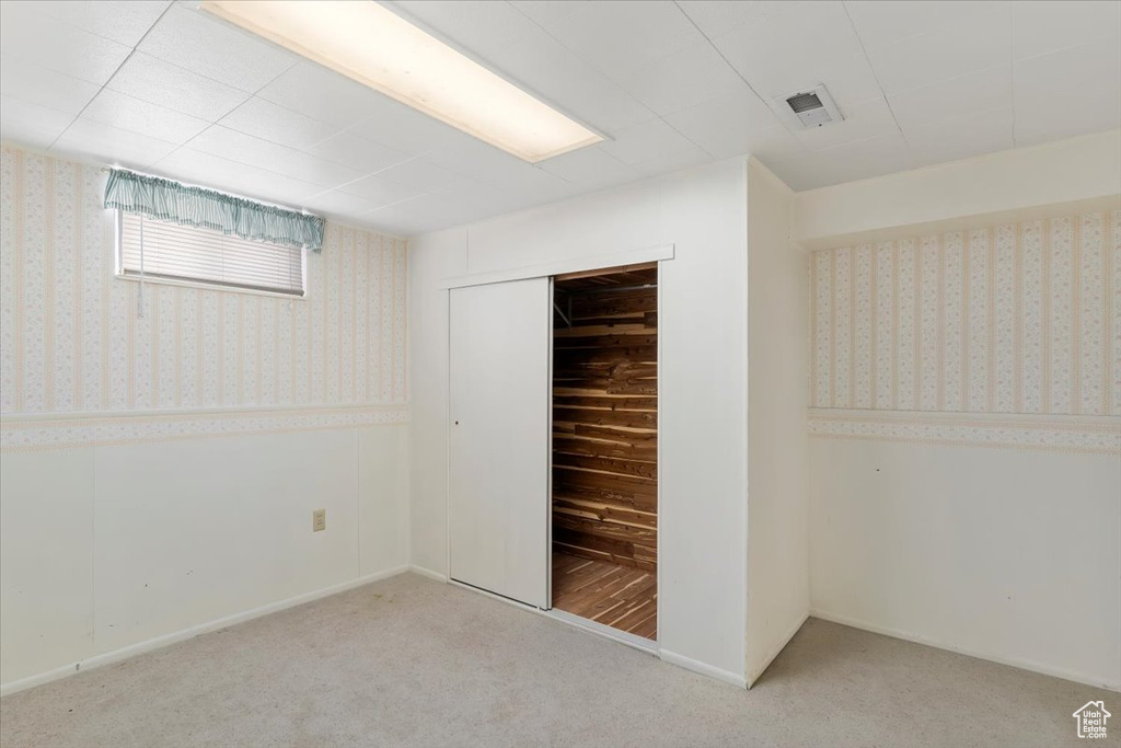 Unfurnished bedroom with carpet, baseboards, wallpapered walls, visible vents, and a closet