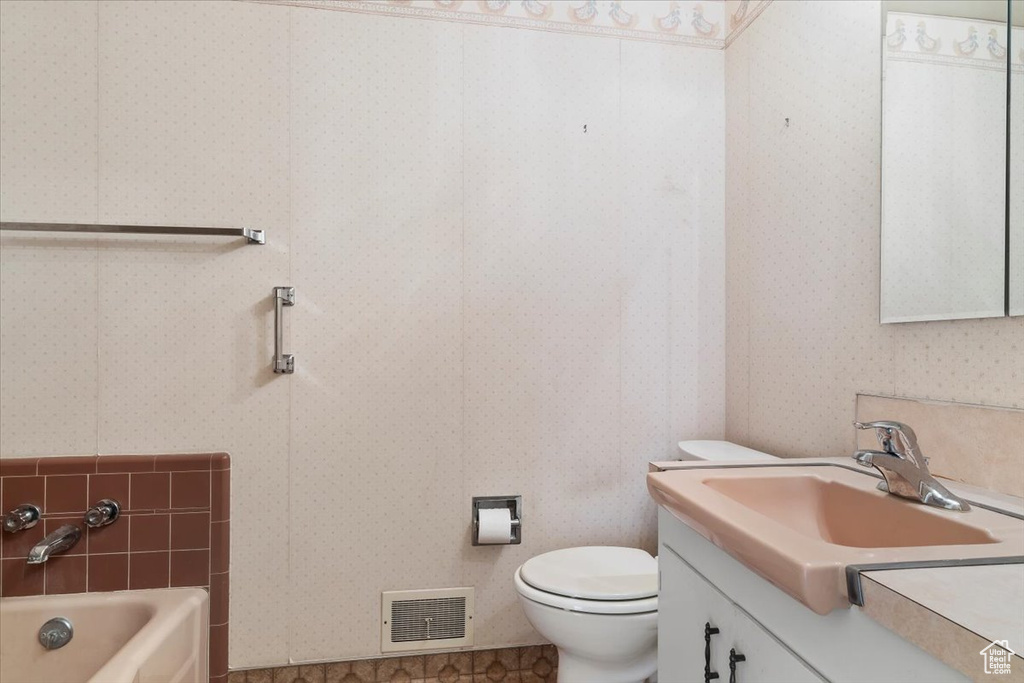 Bathroom with toilet, visible vents, a bathing tub, and wallpapered walls