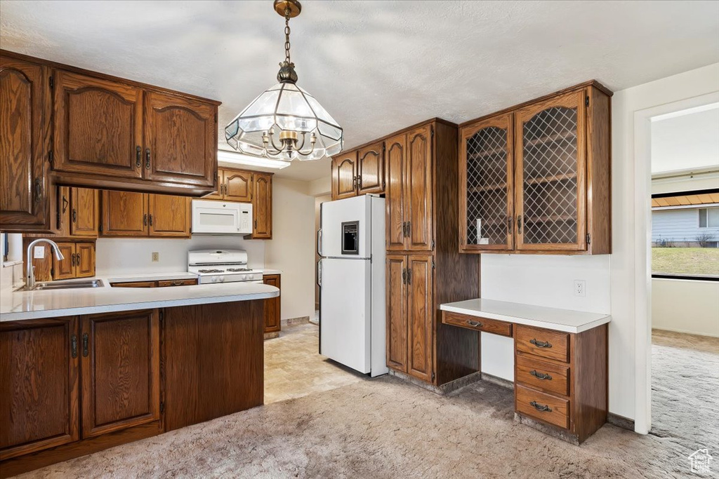 Kitchen with light countertops, a chandelier, white appliances, light carpet, and a sink