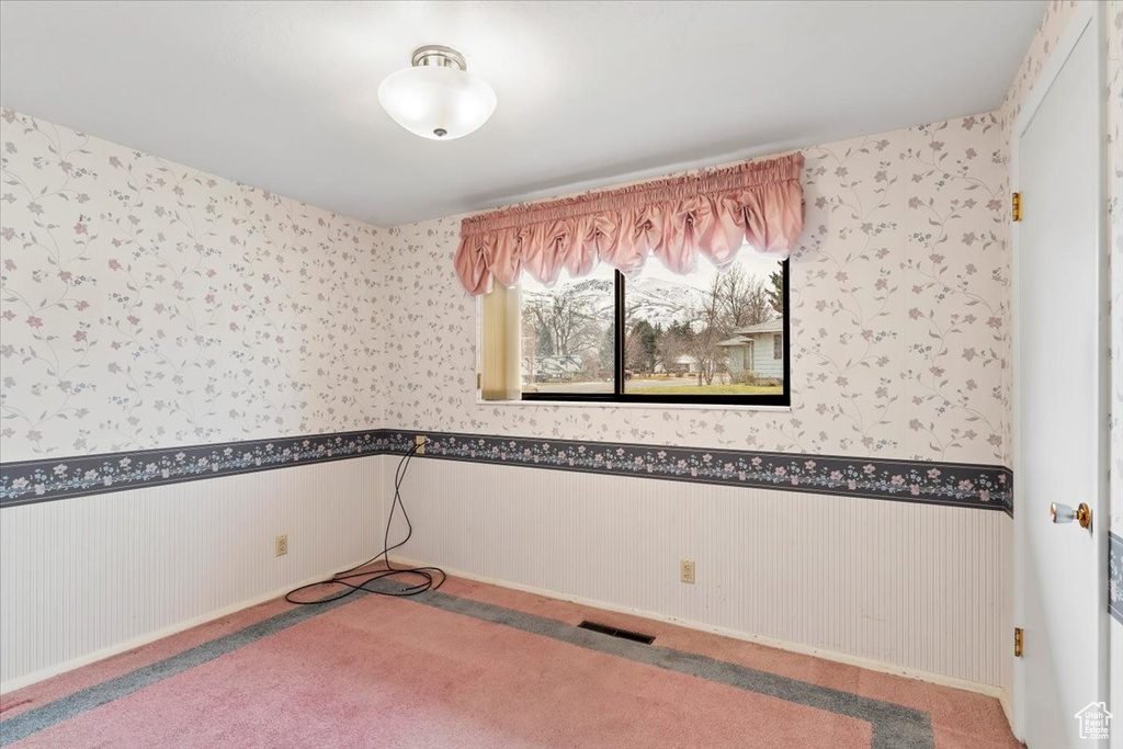 Spare room featuring wallpapered walls and a wainscoted wall