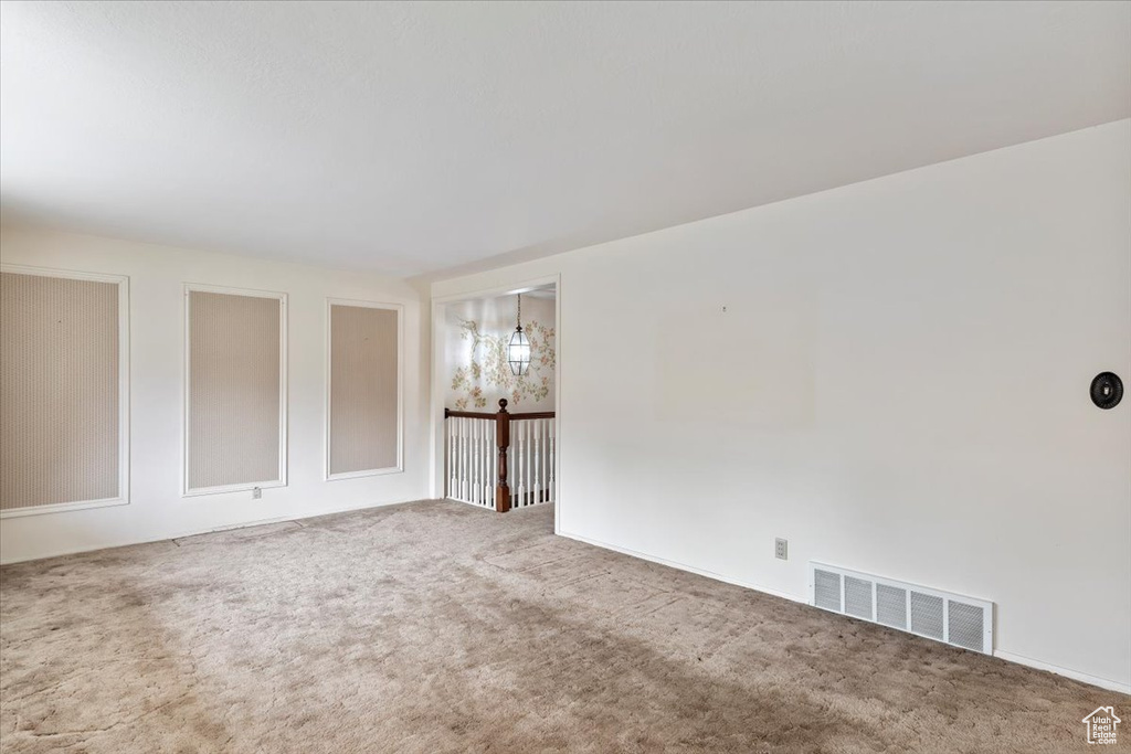 Carpeted spare room featuring visible vents