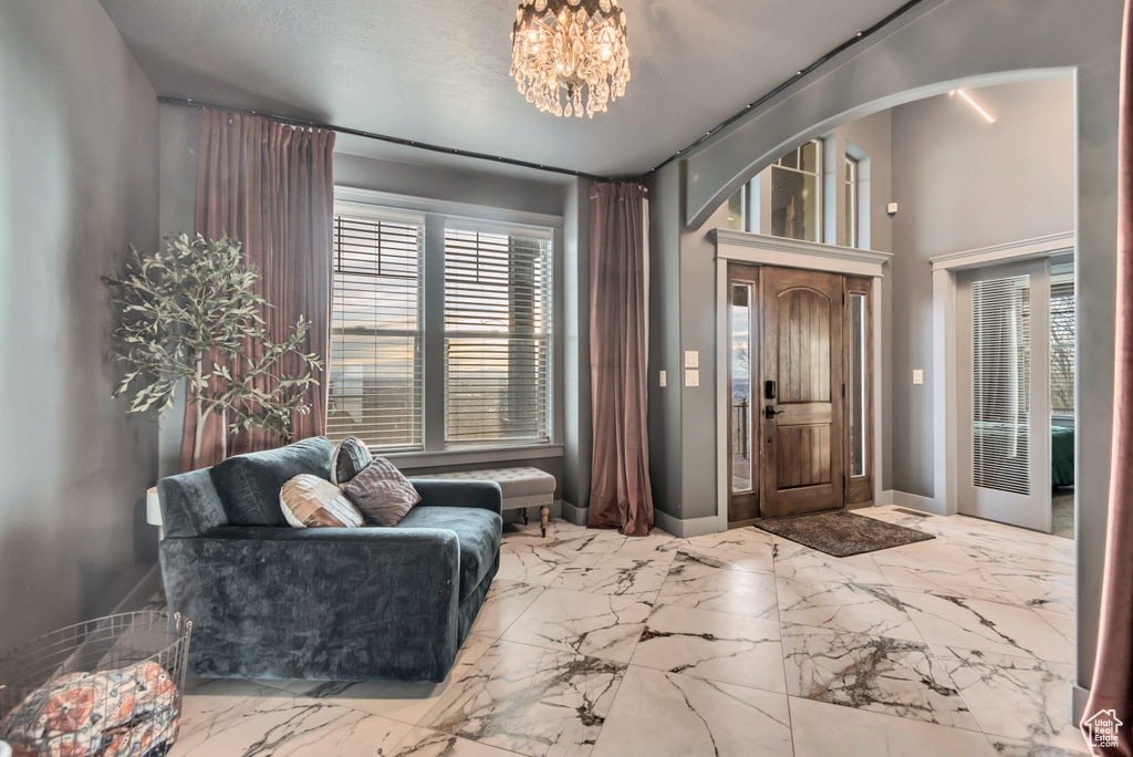 Foyer with marble finish floor, baseboards, a notable chandelier, and arched walkways