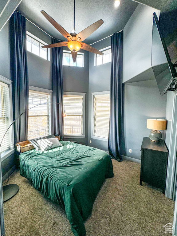 Bedroom with carpet flooring, a textured ceiling, baseboards, a towering ceiling, and ceiling fan