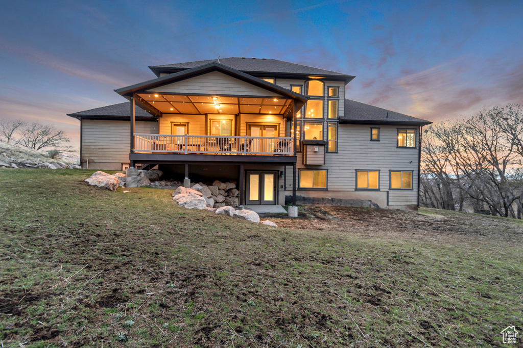 Rear view of property with a deck and a lawn