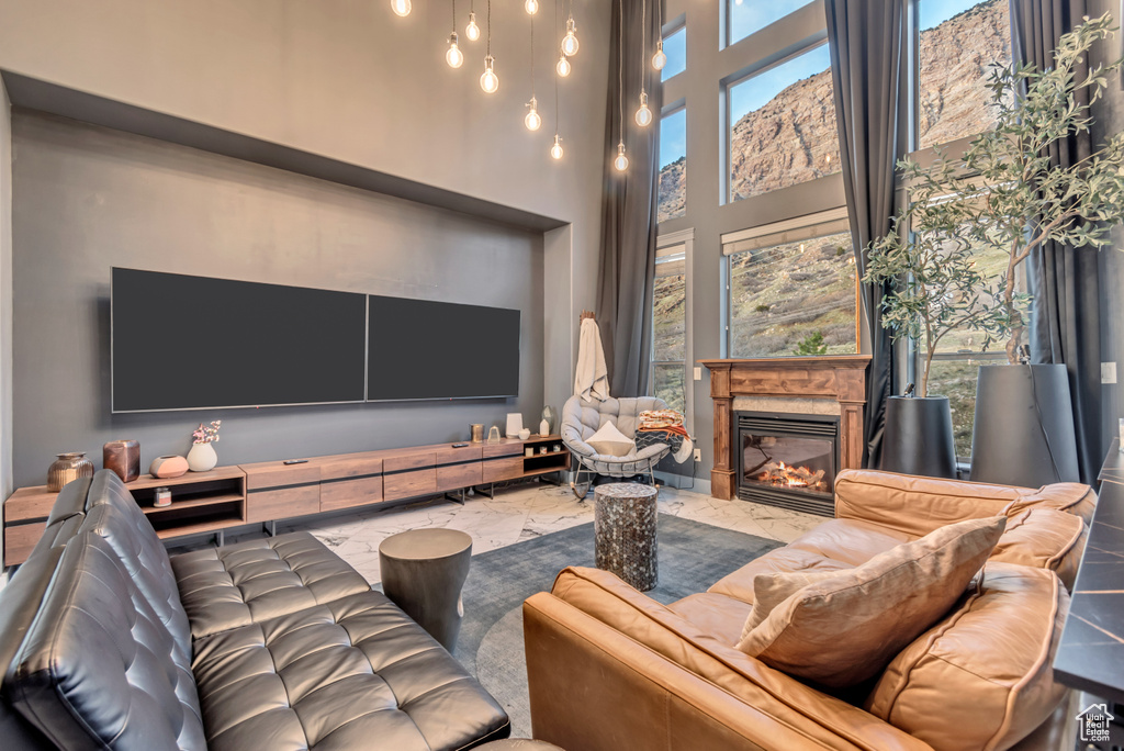 Living room featuring marble finish floor, a fireplace, and a high ceiling