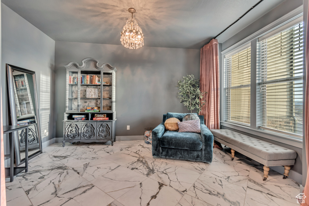 Living area with marble finish floor, baseboards, and an inviting chandelier