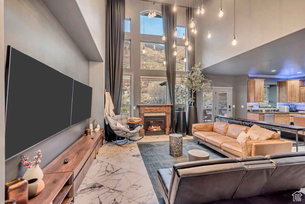 Living area featuring marble finish floor, recessed lighting, a towering ceiling, and a glass covered fireplace