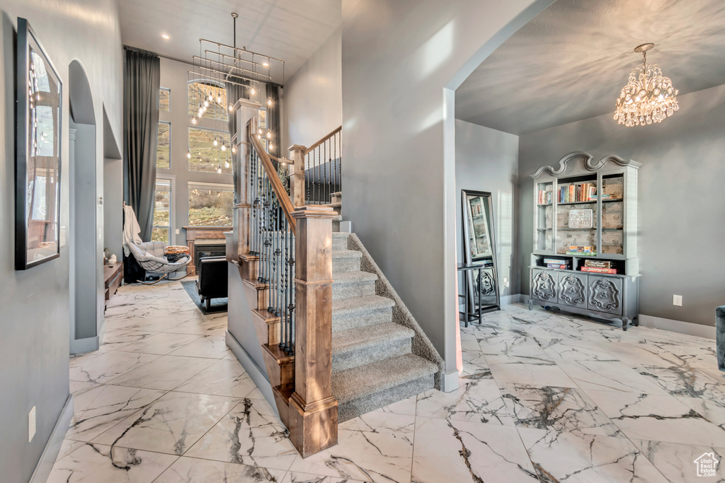 Stairs featuring baseboards, a notable chandelier, arched walkways, and a towering ceiling