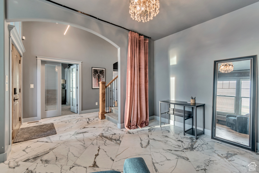 Entrance foyer featuring marble finish floor, arched walkways, and stairs