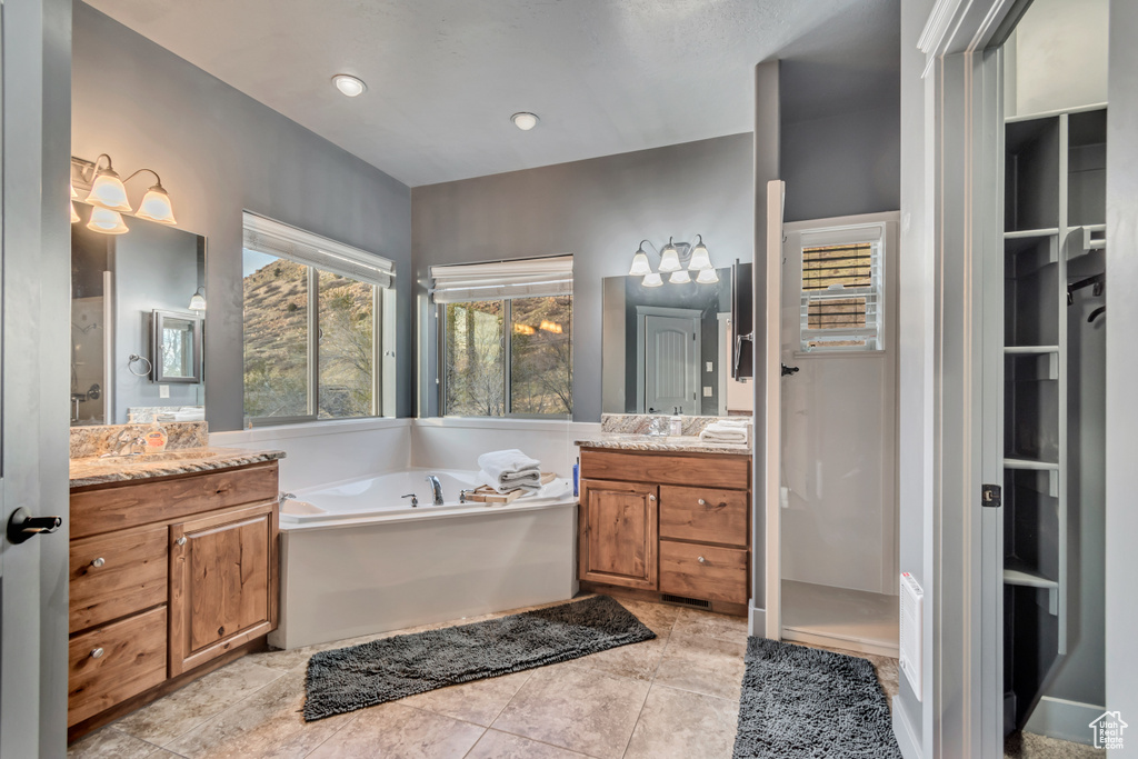 Bathroom with tile patterned flooring, recessed lighting, a garden tub, a notable chandelier, and two vanities