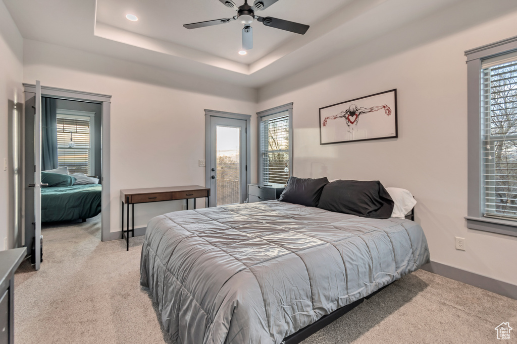 Bedroom with carpet floors, multiple windows, and a raised ceiling
