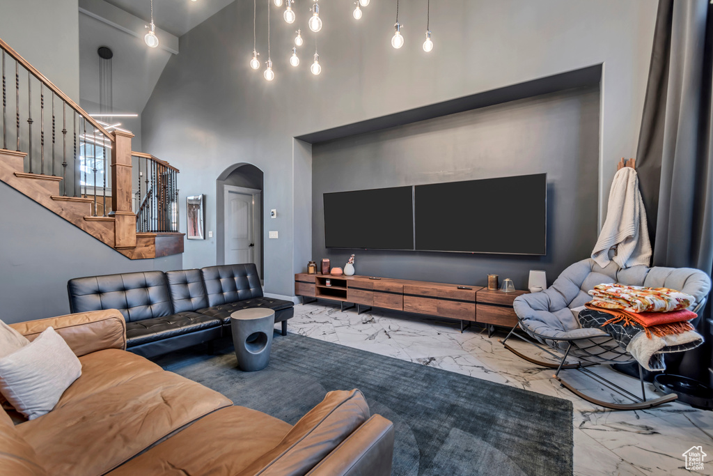 Living area with marble finish floor, a high ceiling, arched walkways, and stairway