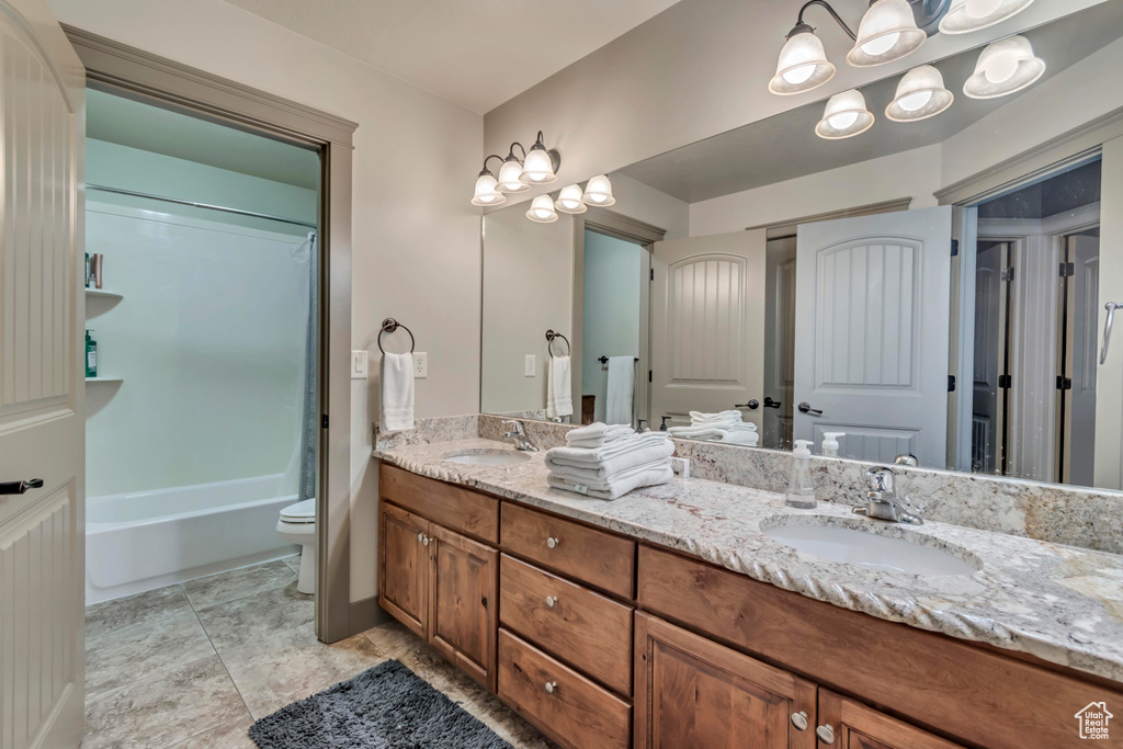 Full bathroom with double vanity, a sink, toilet, and washtub / shower combination