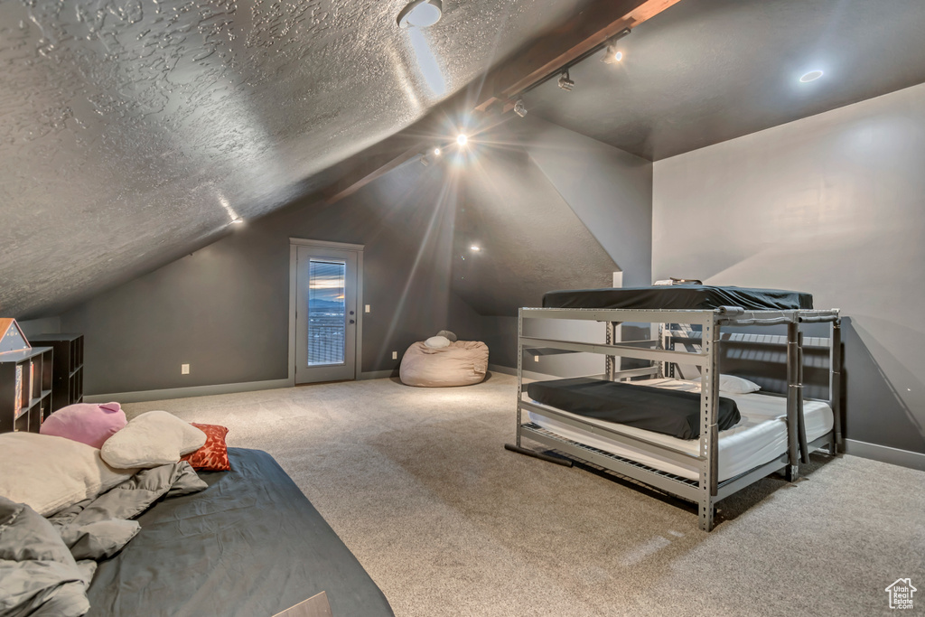 Bedroom with lofted ceiling, carpet, baseboards, access to outside, and a textured ceiling