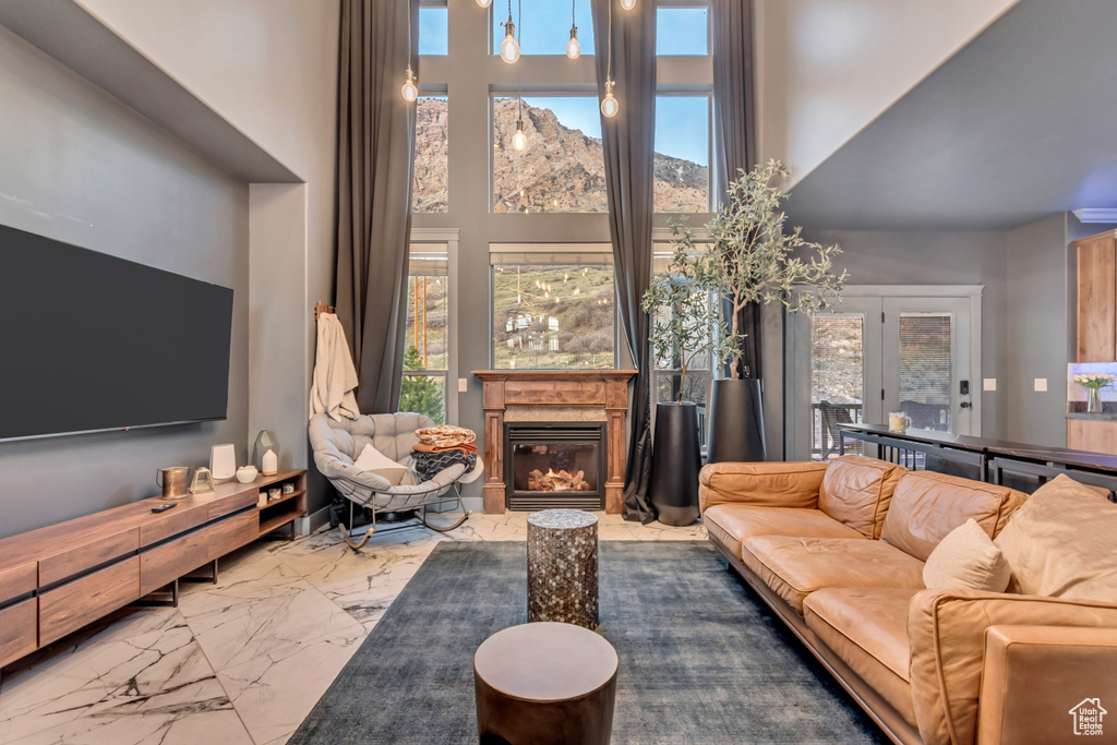 Living area featuring a high ceiling, marble finish floor, and a glass covered fireplace