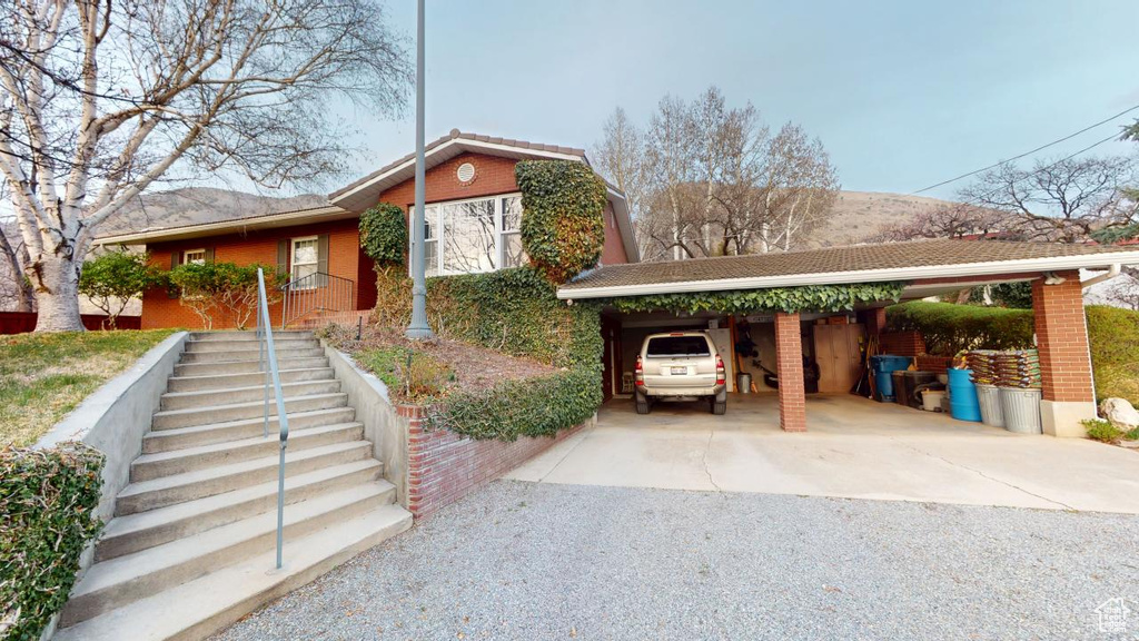 View of front of house with a carport, driveway, and brick siding