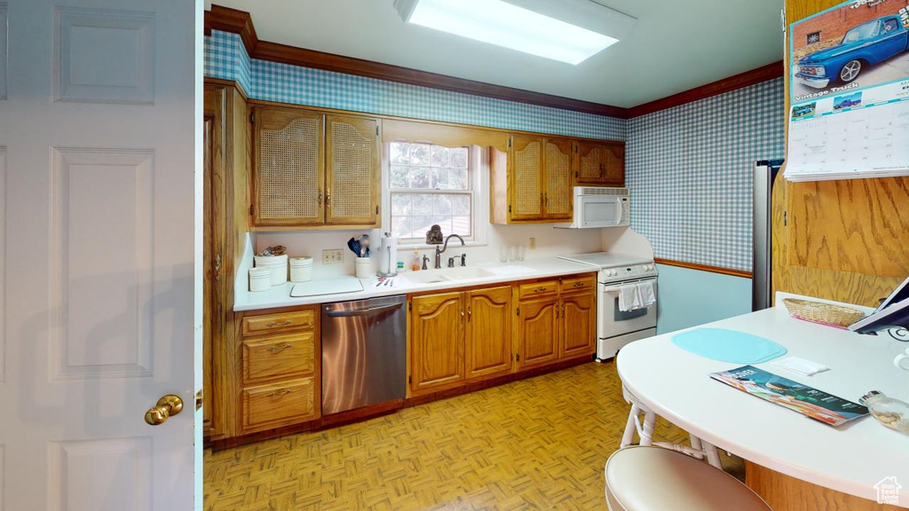 Kitchen featuring wallpapered walls, light countertops, a sink, and appliances with stainless steel finishes