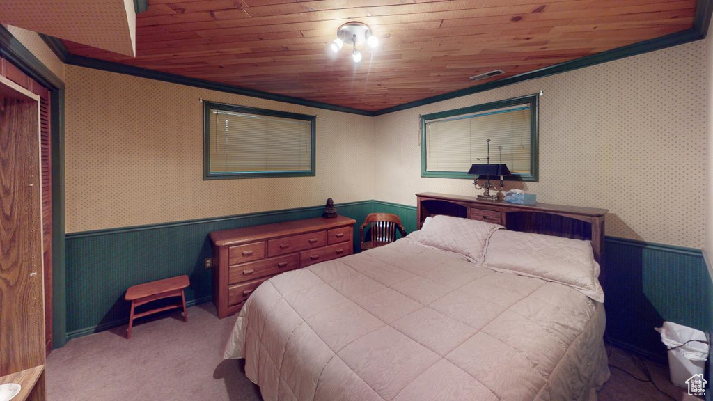 Carpeted bedroom featuring wooden ceiling, wallpapered walls, a wainscoted wall, and crown molding