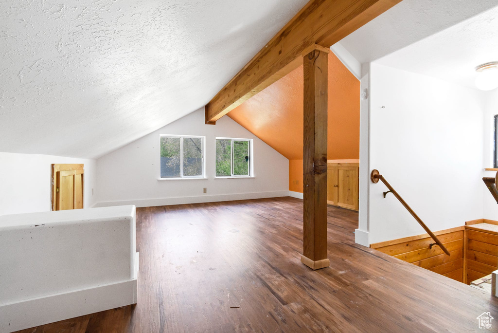 Additional living space with wood finished floors, baseboards, and a textured ceiling