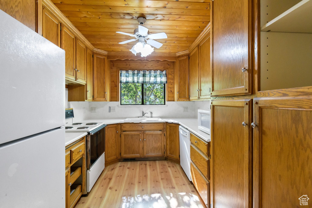 Kitchen with white appliances, light wood-style flooring, a sink, light countertops, and a ceiling fan